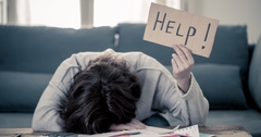 stressed woman holding up help sign