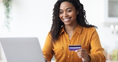 Woman looking at computer holding a credit card