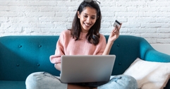 Woman holding credit card and looking at computer