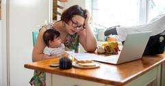 Woman holding baby and looking at computer