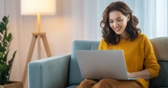 A woman sitting on the couch in her living room, using her laptop.