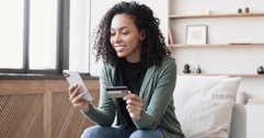 Woman holding her phone in one hand and credit card in the other