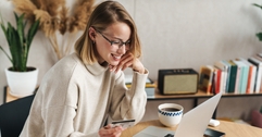 Smiling woman holding a credit card and looking at a computer
