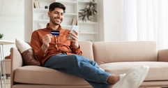 Smiling man looking at his credit card and phone