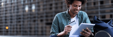 A smiling man holds a credit card and tablet.