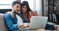 Couple sitting together on couch and looking at computer screen together
