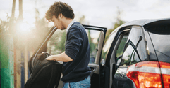 teen with backpack standing outside car