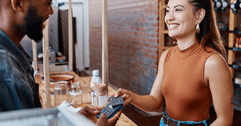 A woman uses her credit card to make a purchase at a cafe.