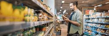 Man looking at an item in his hands while shopping at the grocery store