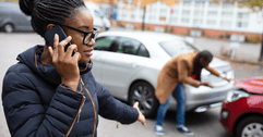 A woman makes a phone call after being in a car accident.