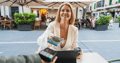 A woman smiles while using her phone to make a payment.