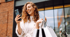 person looking at phone holding shopping bags