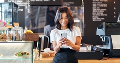 Person working at cafe using their mobile phone in front of the counter