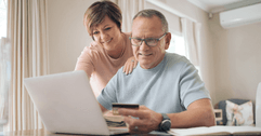 Older couple on laptop using credit card