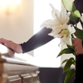 woman with lily flowers and coffin at funeral