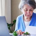 senior lady reading document and working on laptop