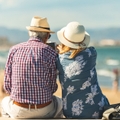 elderly couple sitting on the wall facing the beach