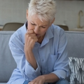 upset older woman sit on sofa manages finances