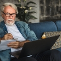 elderly man writing notes in notebook