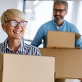 senior couple happily moving into house holding moving boxes
