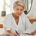 senior woman with notebook writing budget plan
