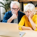 elderly couple is looking puzzled on the laptop screen