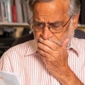 senior man looking at utility bills and covering face in terror