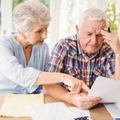 senior couple sitting at table reviewing taxes while doing calculations 
