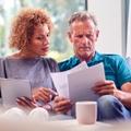 worried senior couple sitting on sofa