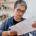 senior woman reading bills in kitchen