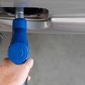 Hand holding blue gas pump nozzle
