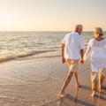 retired couple walking holding hands on beach