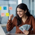happy young businesswoman holding money