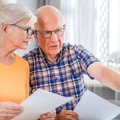 Worried senior couple checking bills using laptop
