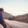person leaning against car by side of road