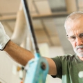 Older worker threading a steel bar in an industrial factory