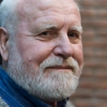 close up of a 70 year old man with a brick wall in the background