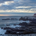 Maine lighthouse in background with ocean shoreline in foreground