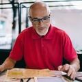 Bald man wearing glasses and looking at papers on the table