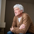 Senior man sits staring blankly out window
