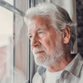 contemplative older man looking out window