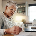 senior woman doing paperwork with laptop