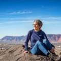Older woman sitting on a rock during hike in mountain desert