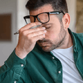 person rubbing eyes at desk