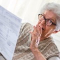 Retired senior woman looking at document worried