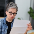 Confused Gen X retired woman reviewing a letter