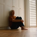 Sad Senior Woman Sitting On Floor At Home 