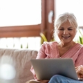 Smiling retired couple on the couch with laptop