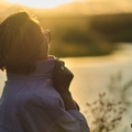 Retiree woman overlooking a river at sunset