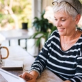 Woman with short, white hair sitting at the table reading a letter and having coffee